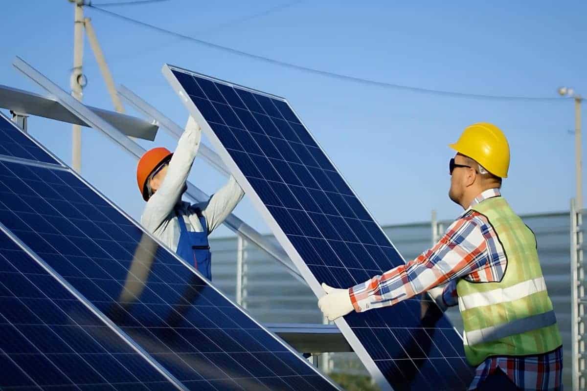 professional cleaners holding a large solar panel